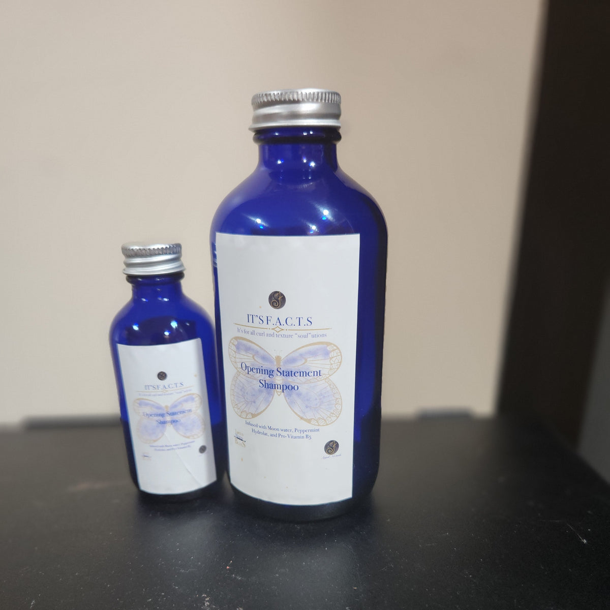 2 oz and 8 oz cobalt blue bottles of Opening Statement Shampoo